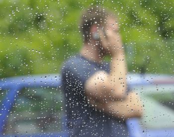 Woman standing on wet glass window in rainy season