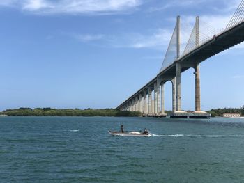 People on bridge over river against sky