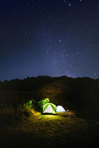 Illuminated tent on field against sky at night