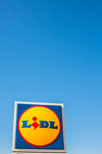 Low angle view of road sign against clear blue sky