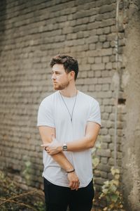 Young man standing against brick wall