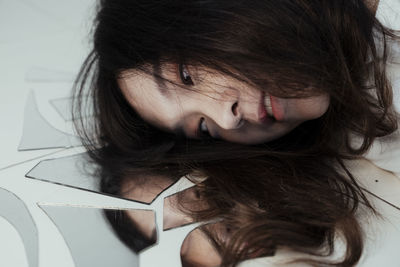 Woman by broken mirror with reflection on floor