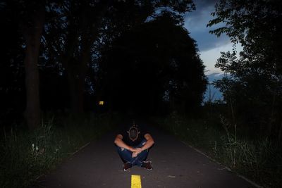 Rear view of woman standing on road amidst trees