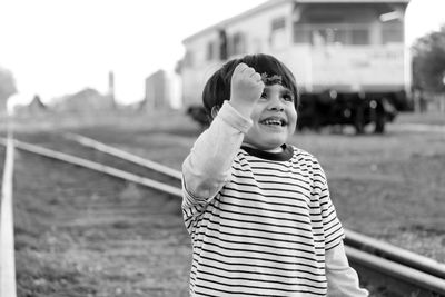 Happy boy holding leaf while standing on railroad track