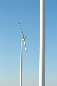 Low angle view of wind turbine against blue sky