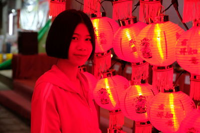 Portrait of woman standing by illuminated lanterns at night