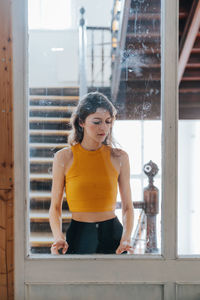 Young woman looking through window