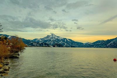 Scenic view of lake by mountains against sky during sunset