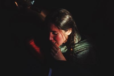 Portrait of woman looking away while sitting in dark