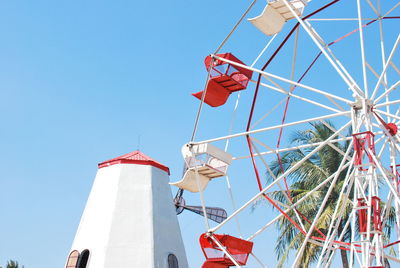 Low angle view of ferris wheel against clear blue sky