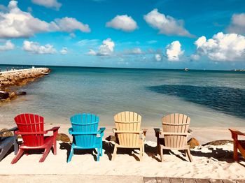 Chairs and tables on beach against sky