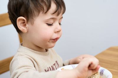 Little boy eating oatmeal for breakfast in the kitchen