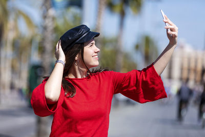 Smiling teenage girl wearing red top in city during sunny day