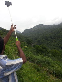 Close-up of man holding umbrella against mountain range