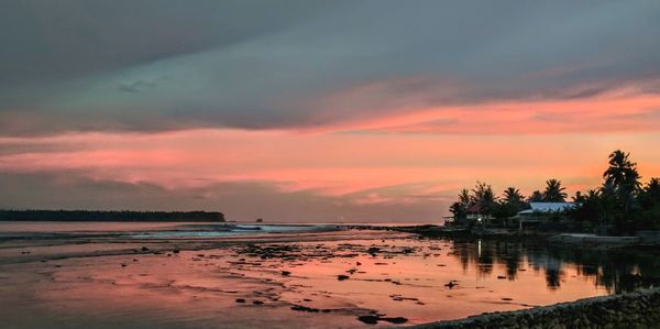 Scenic view of beach against dramatic sky during sunset