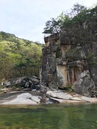 Scenic view of waterfall by cliff against sky