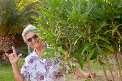 Young woman wearing sunglasses standing by plants