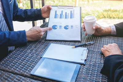 Midsection of businessmen discussing over graph at desk