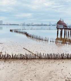 Wooden posts on beach against sky