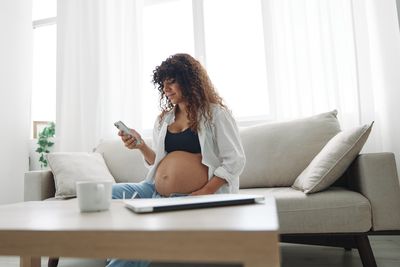 Young woman using laptop while sitting on sofa at home