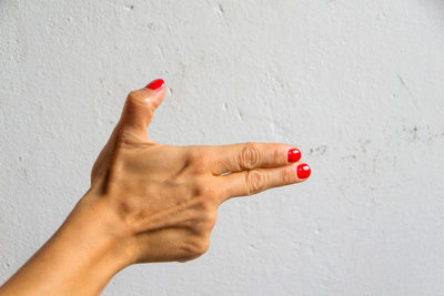 Close-up of woman hand against red wall