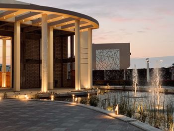Bridge over river against buildings in city at sunset