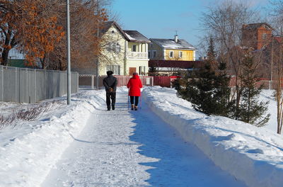 Rear view of people walking on snow covered building