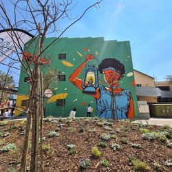 Graffiti on building by trees against sky