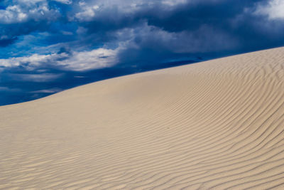 Scenic view of desert against cloudy sky