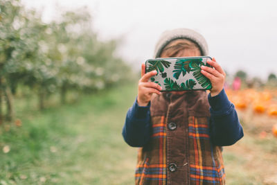 Boy using mobile phone while standing on field