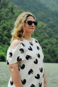 Portrait of young woman standing against mountain