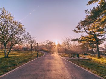 Road amidst trees against sky during sunset