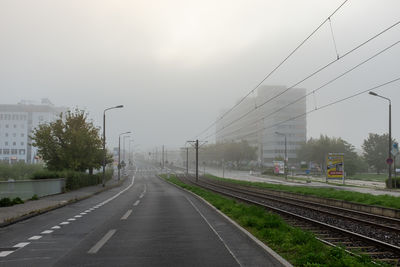 Railroad tracks by road against sky