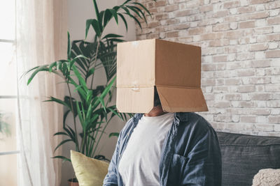 Man covering face with cardboard box at home