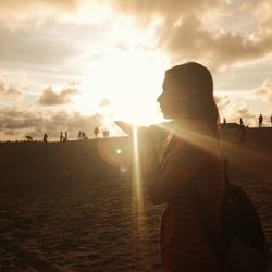 Girl standing in front of sunbeam in desert