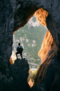 Rear view of man standing on rock in cave