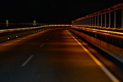 Illuminated light trails on road against sky at night