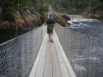 Rear view of man standing on footbridge