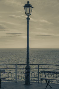 Street light by sea against sky