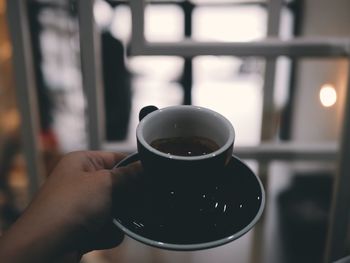 Cropped hand of person holding coffee cup in cafe