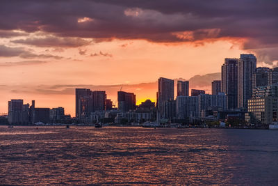 Modern buildings in city against sky during sunset