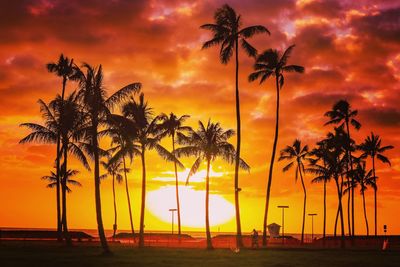Silhouette palm trees at beach against romantic sky during sunset