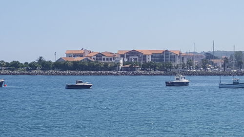 Boats sailing in sea against clear sky