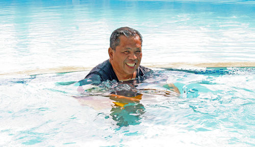 Portrait of smiling mature man swimming in pool