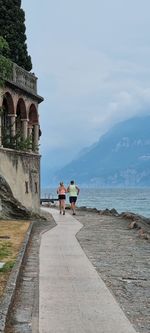 Rear view of people at sea shore against sky