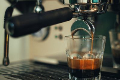 Close-up of coffee pouring in drinking glass