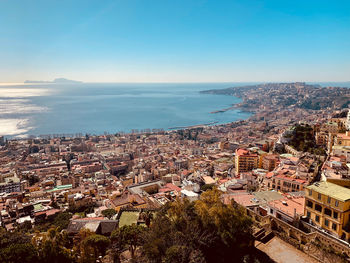 High angle view of townscape by sea against blue sky