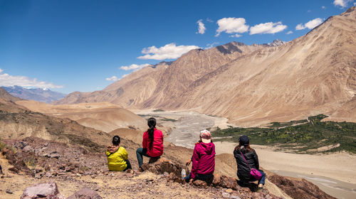 People sitting on rocks against mountains