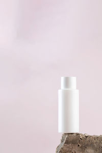 White empty bottle of cosmetics on a concrete podium on a pink background close-up. copy space.