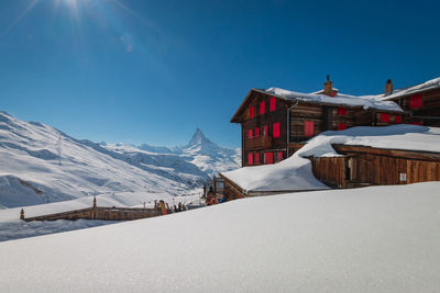 Snow covered houses and mountains against clear sky
